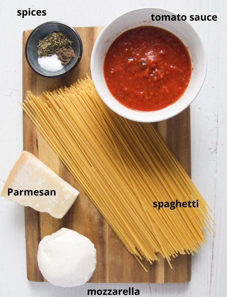 the ingredients for Fried Spaghetti - pasta, mozzarella, parmesan, tomato sauce, spices on a wooden board.