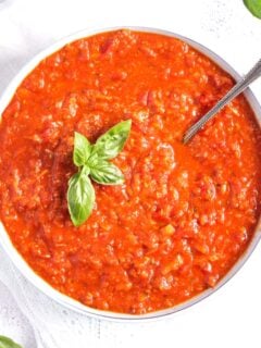 hearty marinara sauce in a white bowl with a spoon in it.