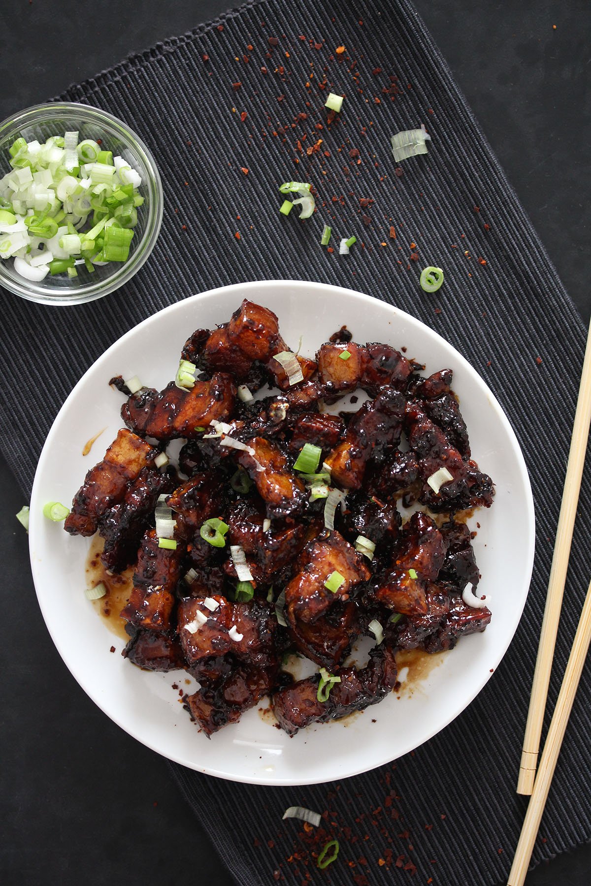 sticky pork pieces with soy sauce on a white plate.