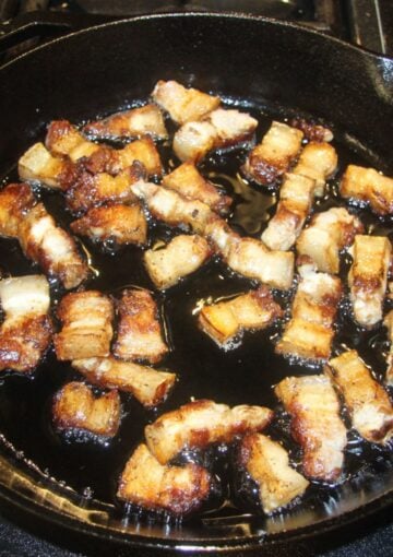 pork belly pieces swimming in their rendered fat in the pan.