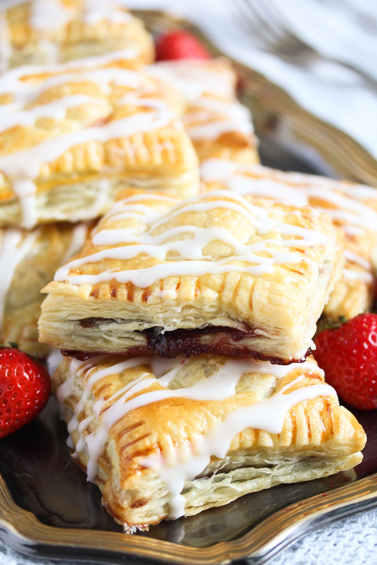 strawberry turnovers stapled on a platter and a few fresh strawberries.