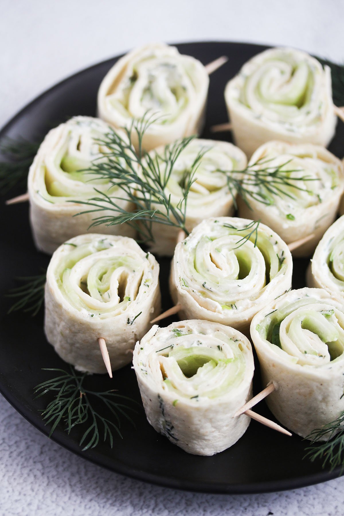 cucumber wraps with cream cheee and dill on toothpicks.