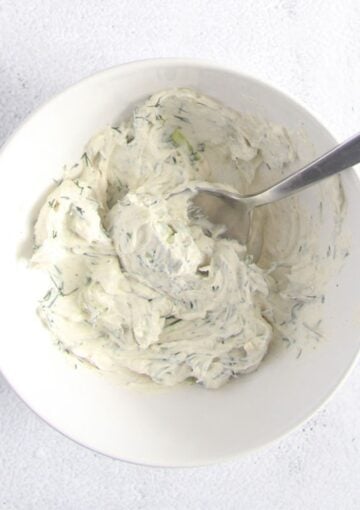 cream cheese mixed with dill in a small bowll with a spoon in it.