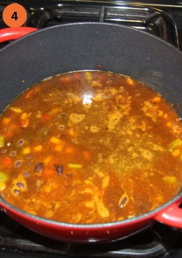 adding black beans and vegetable stock to make soup in a pot.