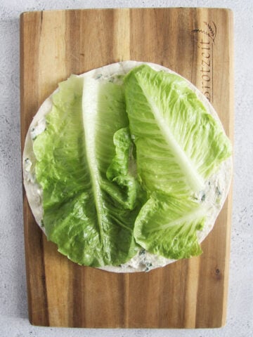 placing lettuce leaves on a tortilla.