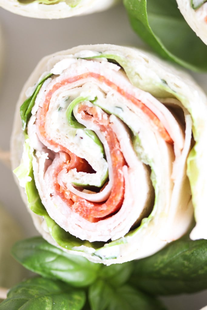 close up of one tortilla pinwheel sandwich stuffed with deli meats and cream cheese.