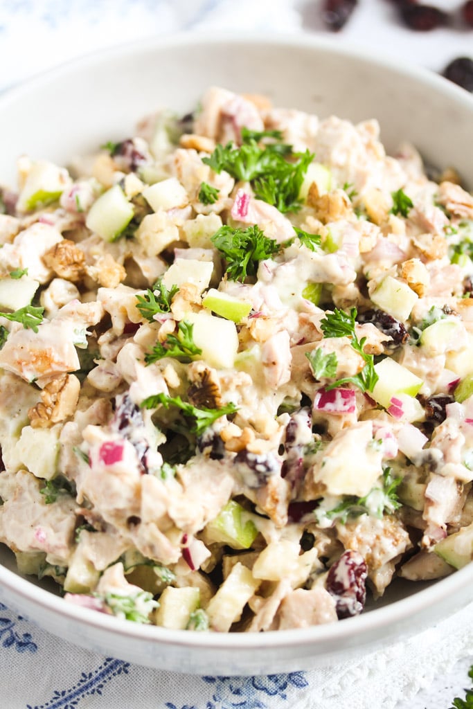 cranberry walnut chickenn salad topped with parsley in a bowl.