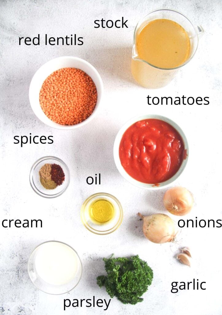 bowls with lentils, stock, tomatoes, spices, oil, cream, onions, garlic, parsley on the table.