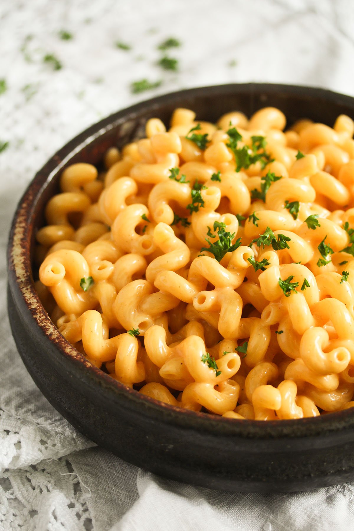 a bowl full of mac and cheese without flour sprinkled with parsley.