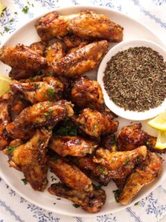 overhead view of a plate with honey lemon pepper wings served with lemon wedges.