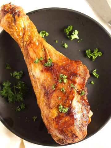 air fryer turkey leg sprinkled with parsley on a plate.