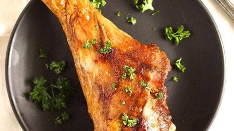 air fryer turkey leg sprinkled with parsley on a plate.