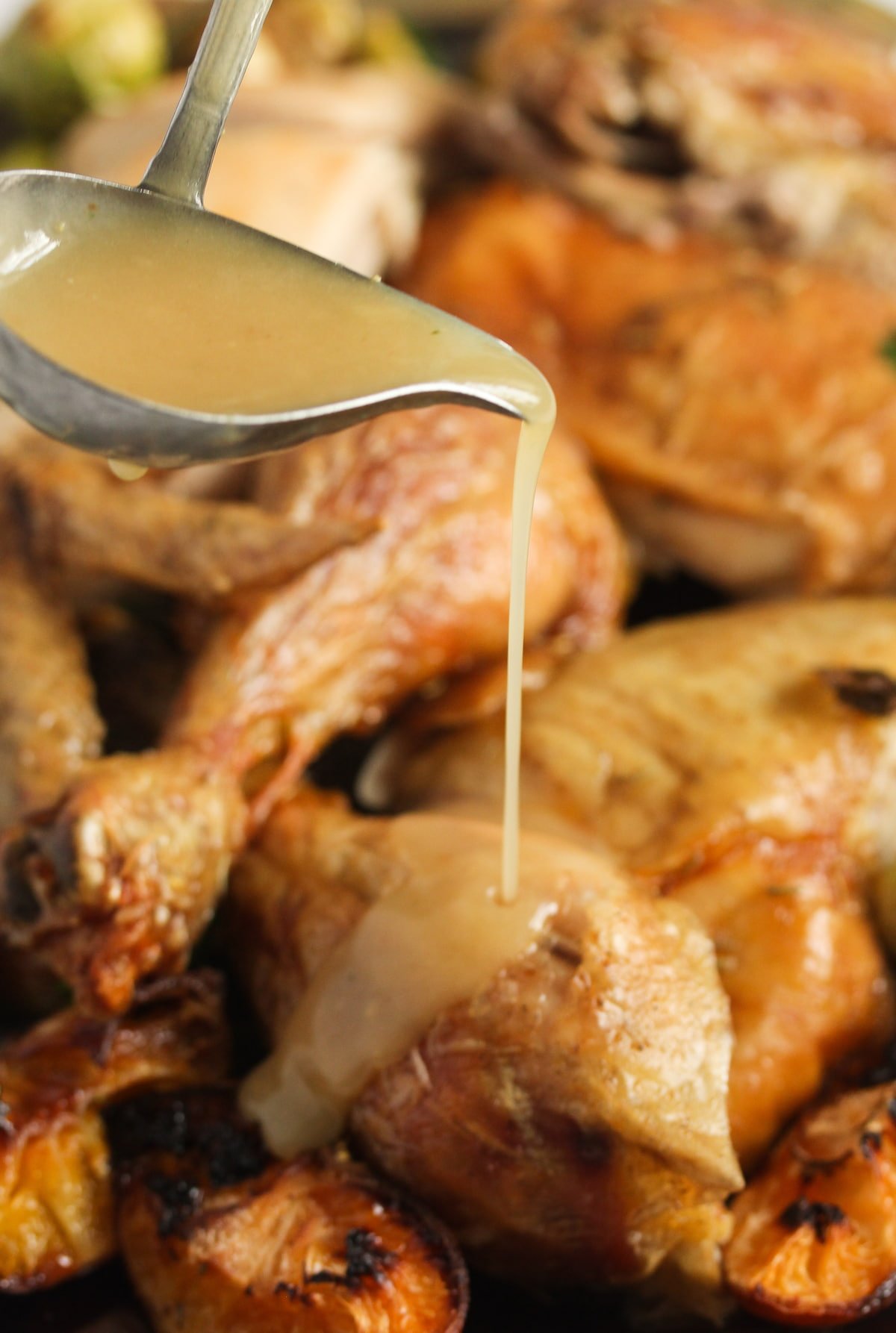 pouring gravy on a platter with roasted chicken pieces.
