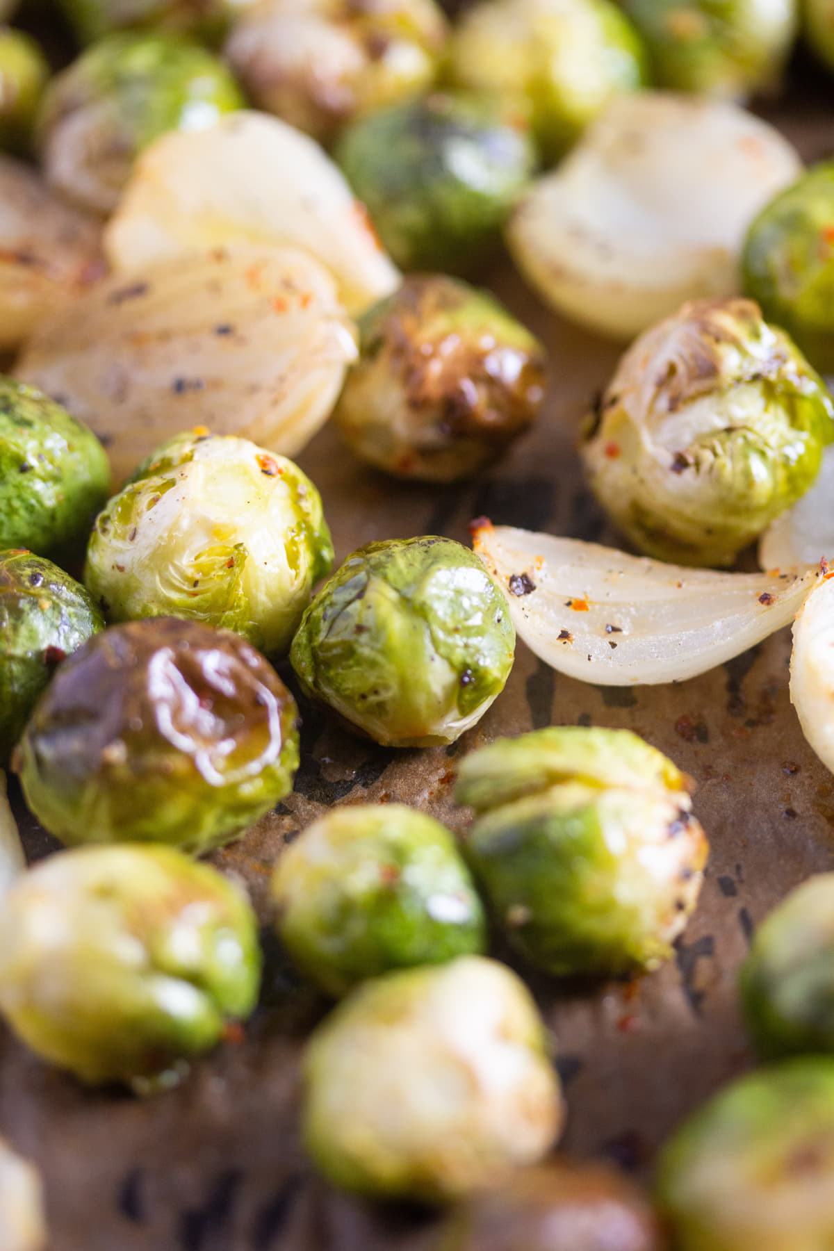 sriracha and honey roasted brussels sprouts and shallots on a baking tray.