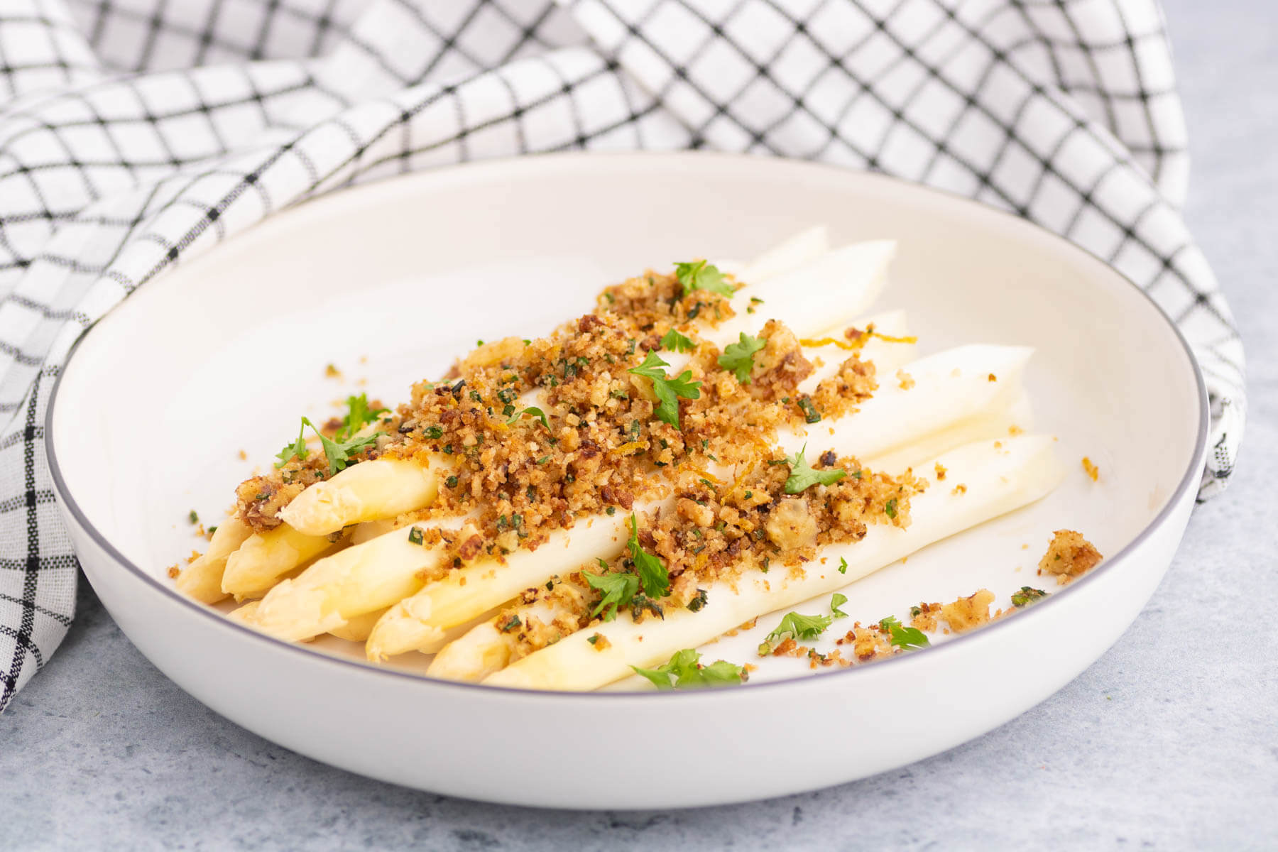 white asparagus with herb pangratto in a white bowl.
