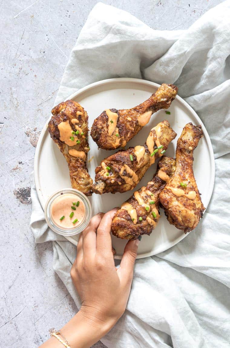 a hand taking a chicken leg from a plate.