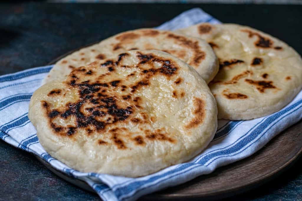 turkish bazlama flatbread on a striped blue and white kitchen cloth.