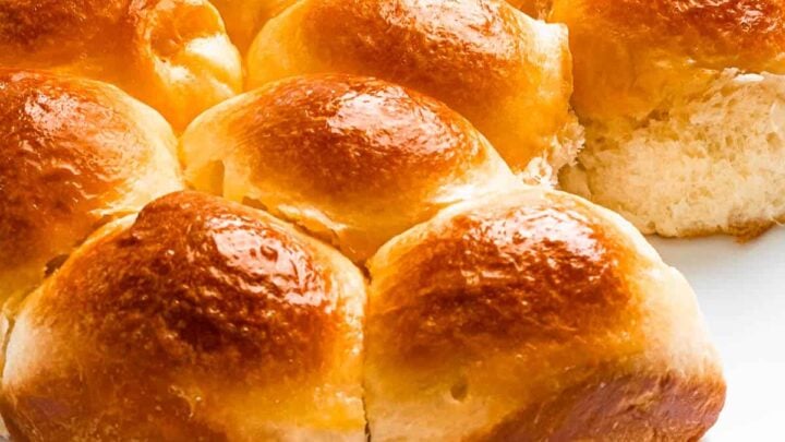 shiny and golden brioche rolls on a white plate.