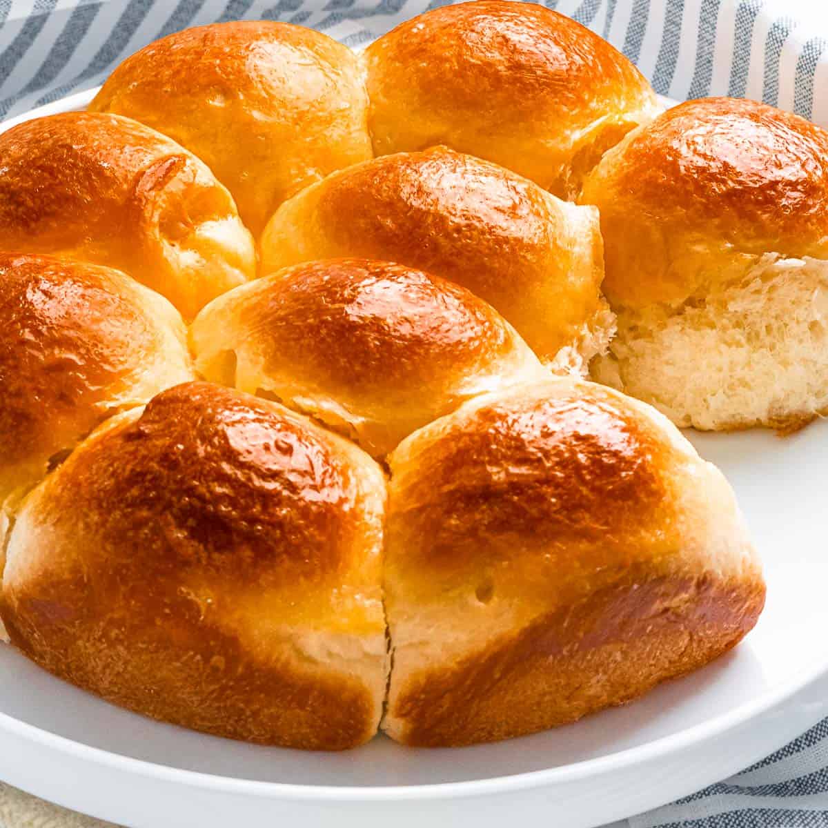 shiny and golden brioche rolls on a white plate.