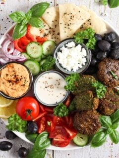 overhead view falafel plate with hummus, tahini, olives, bread.