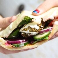 girl's hands holding a falafel sandwich showing the filling.