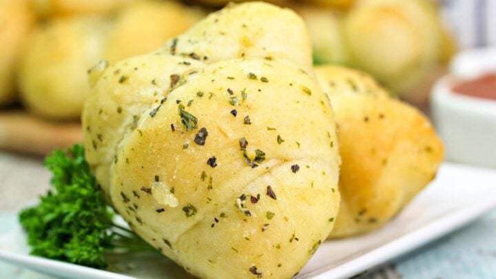 many golden garlic knots on a plate with parsley.