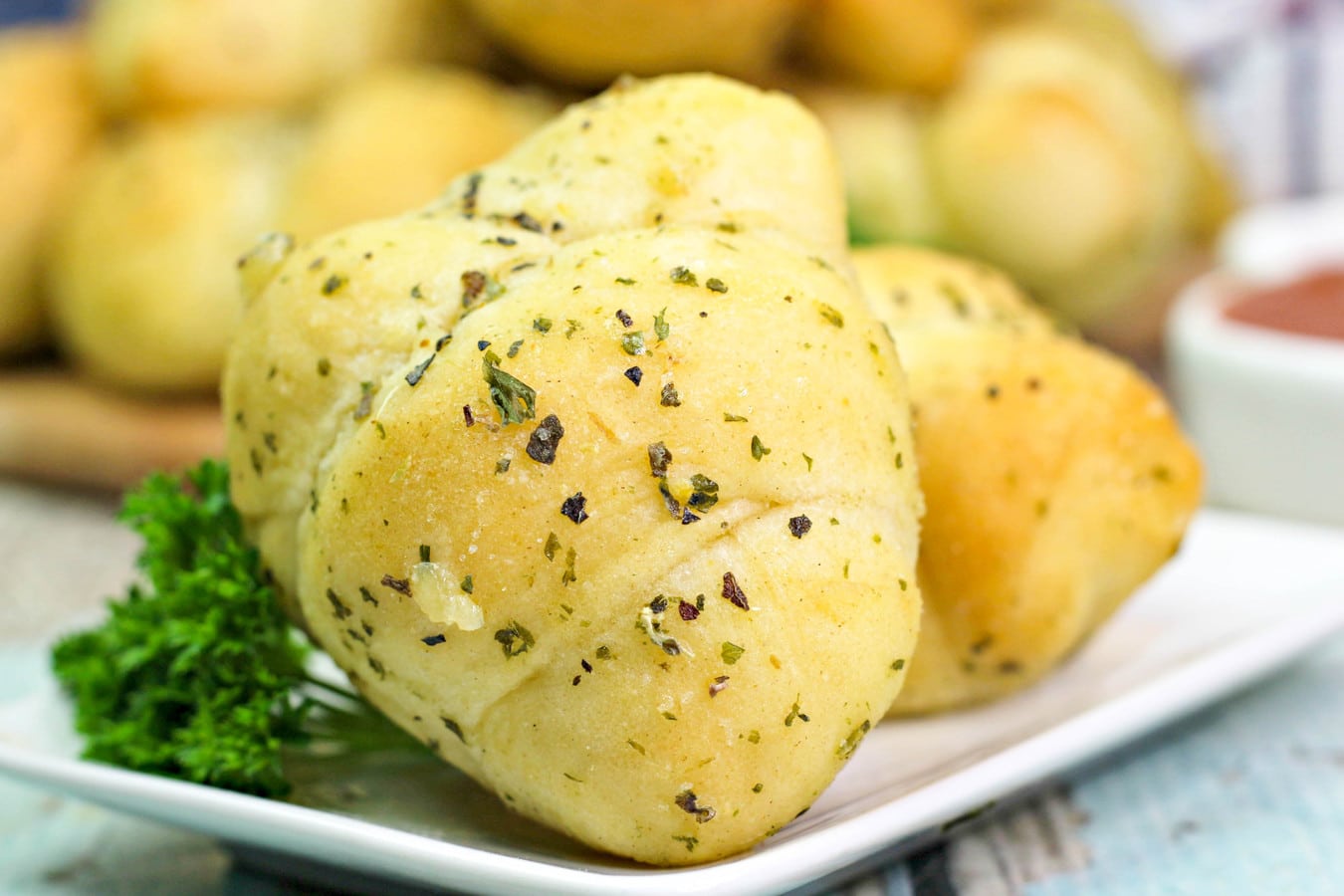 many golden garlic knots on a plate with parsley.