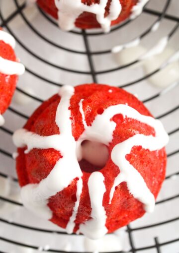 red mini bundt cakes with glaze running down on them.