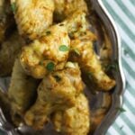 platter with wings seasoned with curry on a green white cloth.