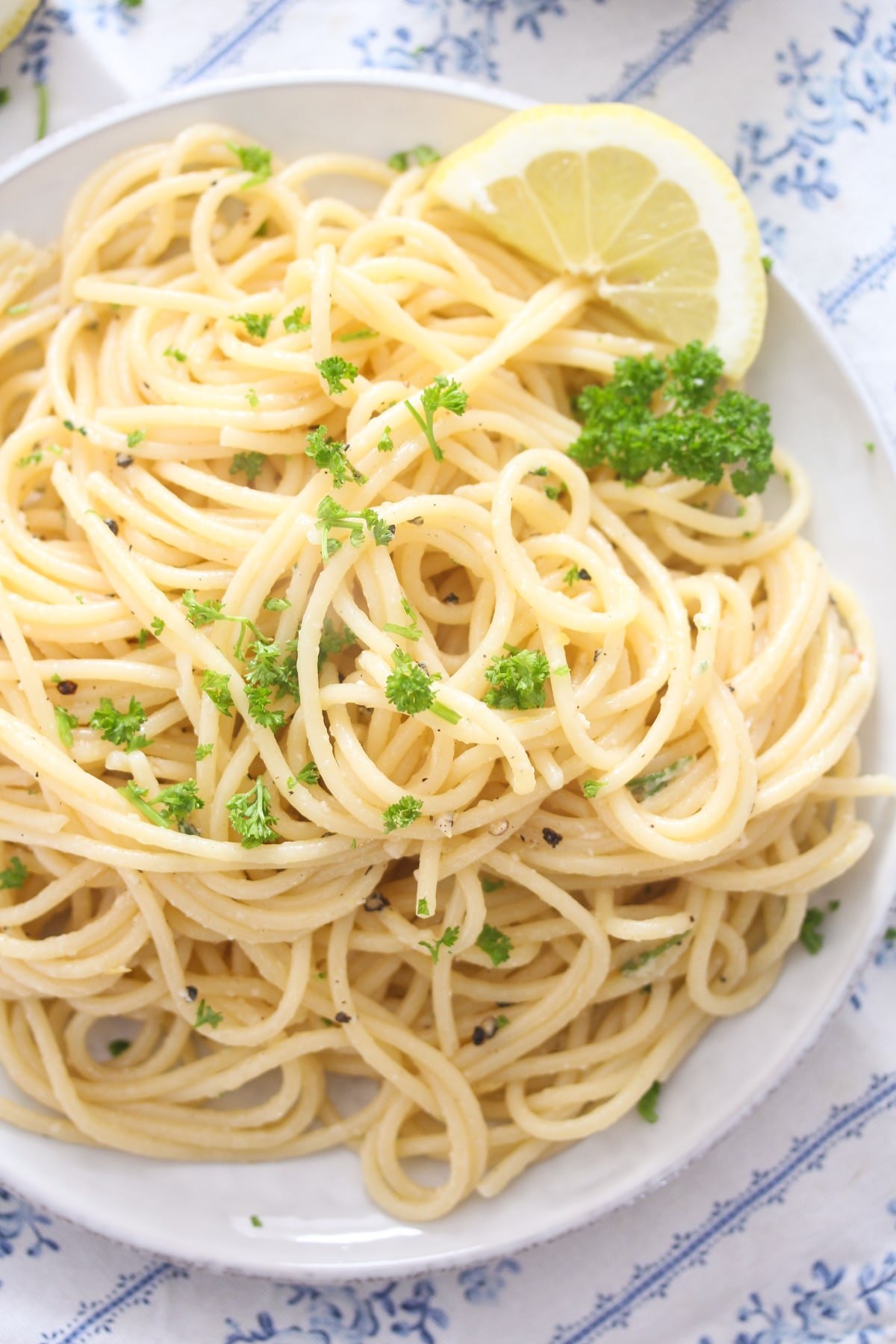 overhead view of a plate of lemon pasta with black perpper, sprinkled with parsley.