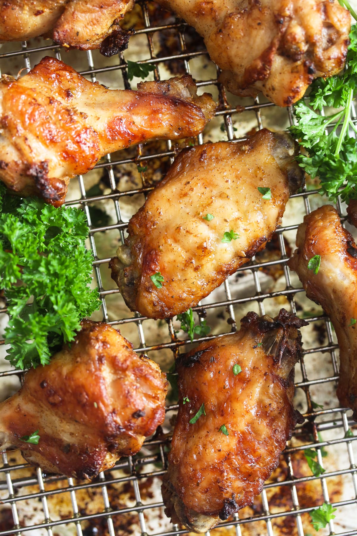 golden garlic butter chicken wings and fresh parsley on a wire rack.