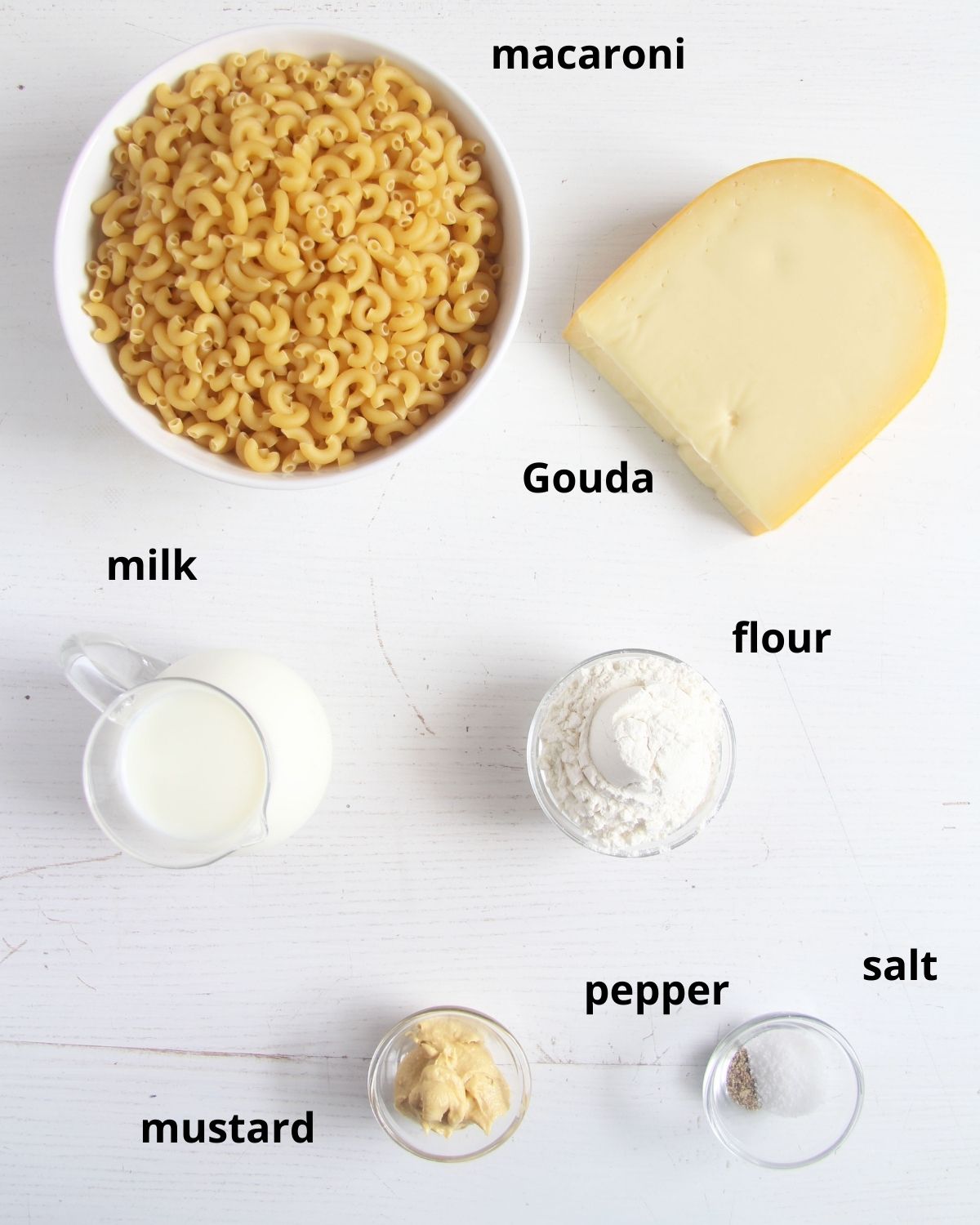 listed ingredients for making mac and cheese with gouda cheese on the table.