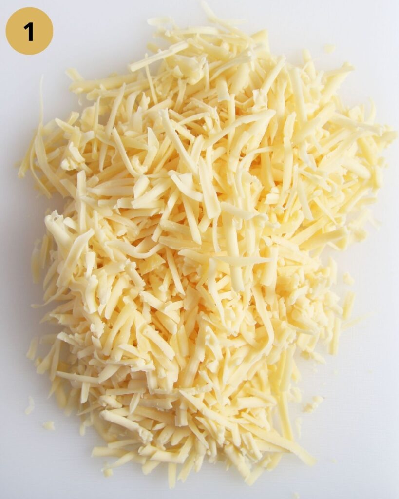 grated gouda on a white cutting board.
