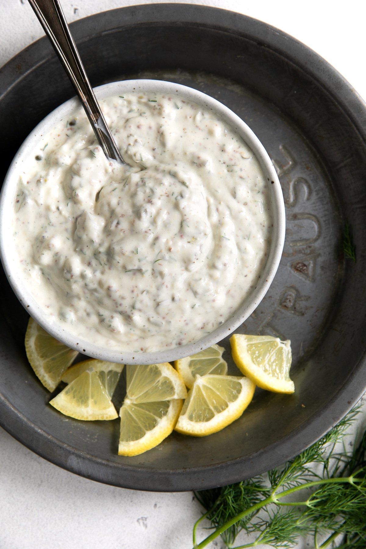 overhead view of bowl with tartar sauce and lemon slices.