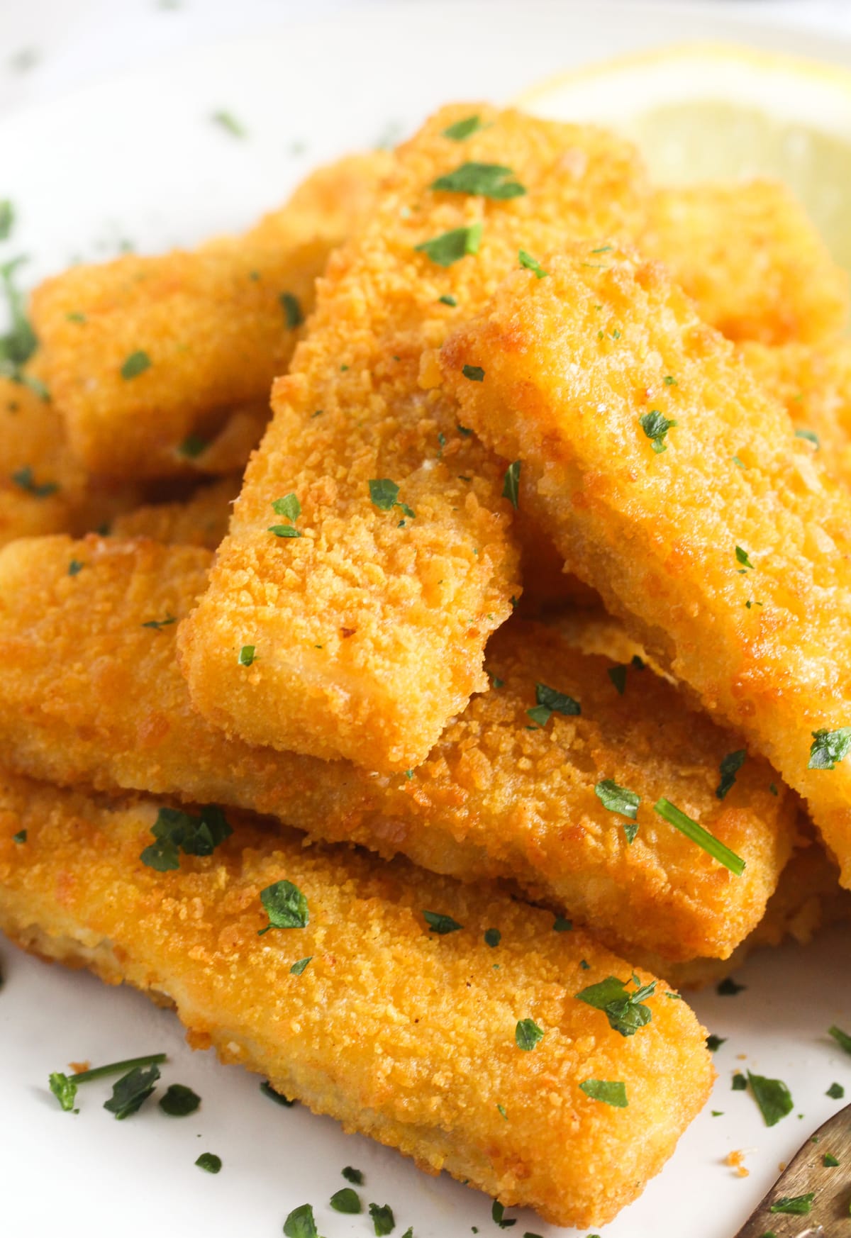 close up golden fish fingers sprinkled with parsley.