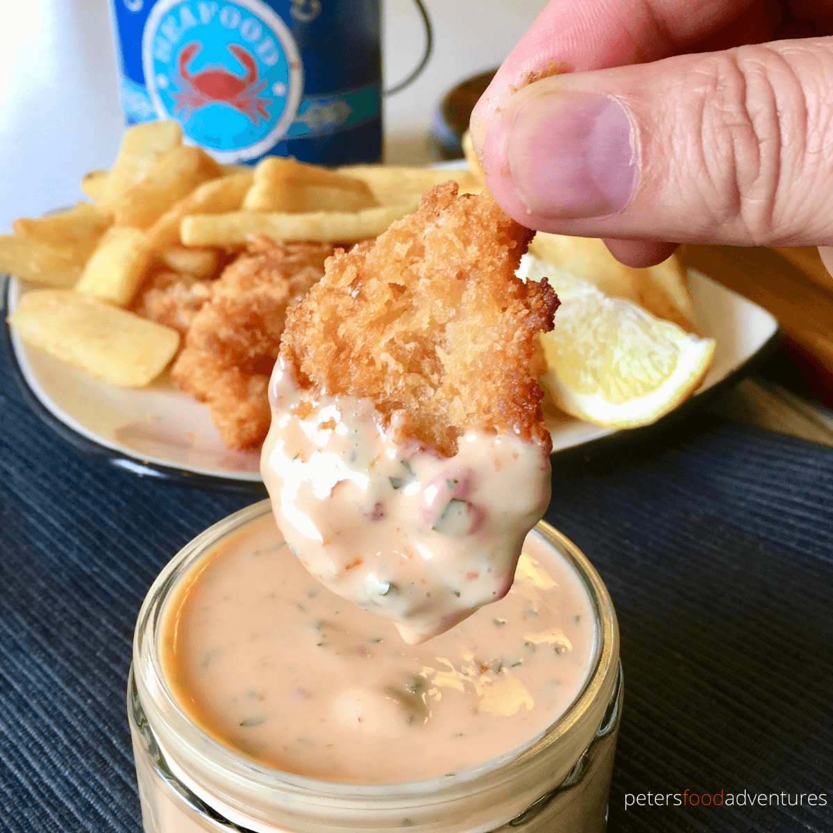 hand dipping a nugget in sweet chili sauce.