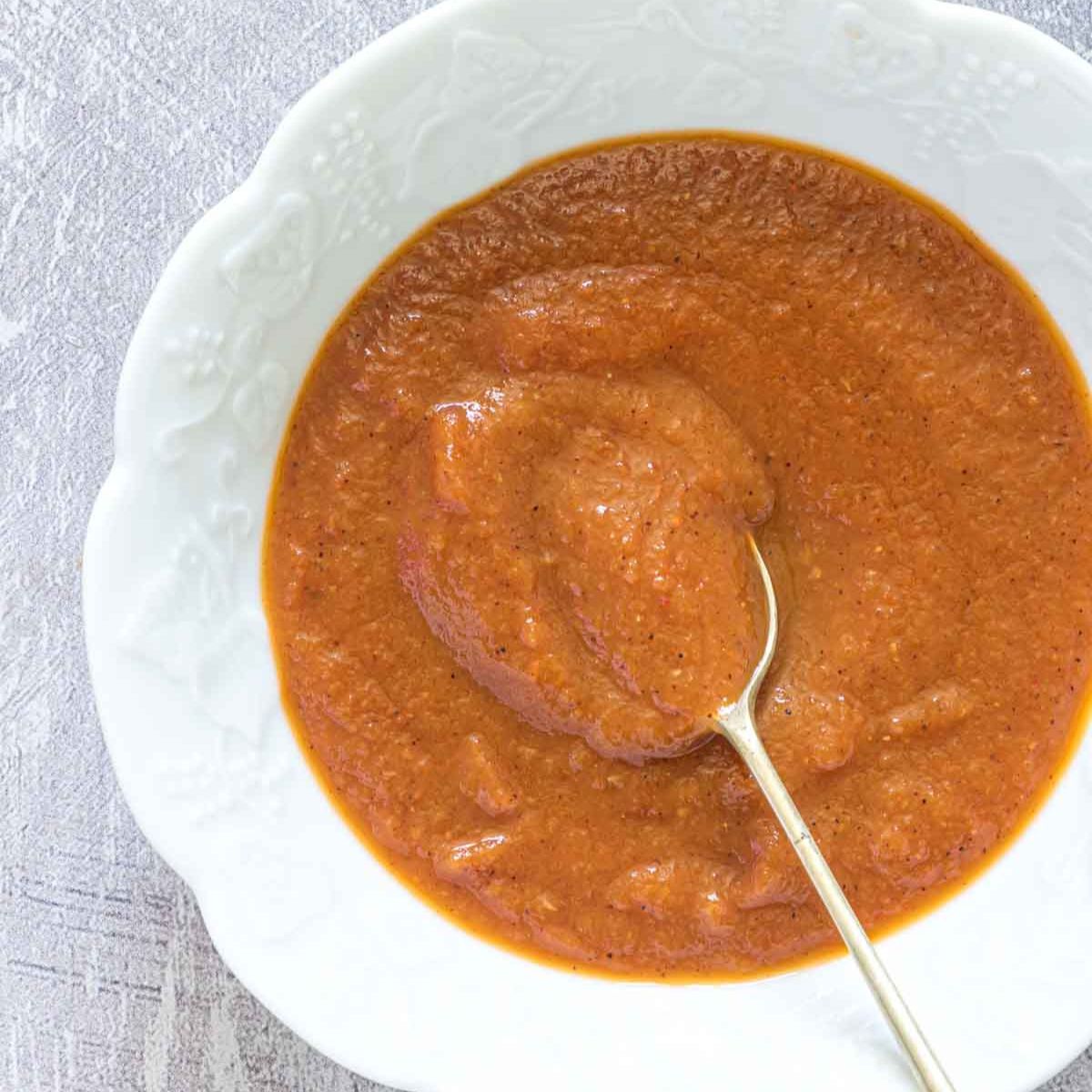 homemade ketchup on a plate with a spoon in it.