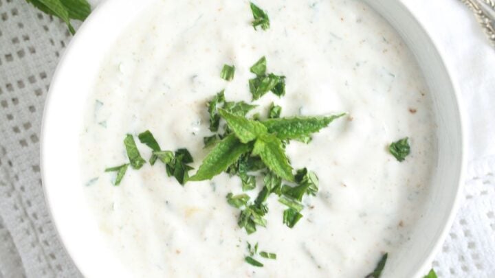 bowl with yogurt mint sauce on a white cloth.