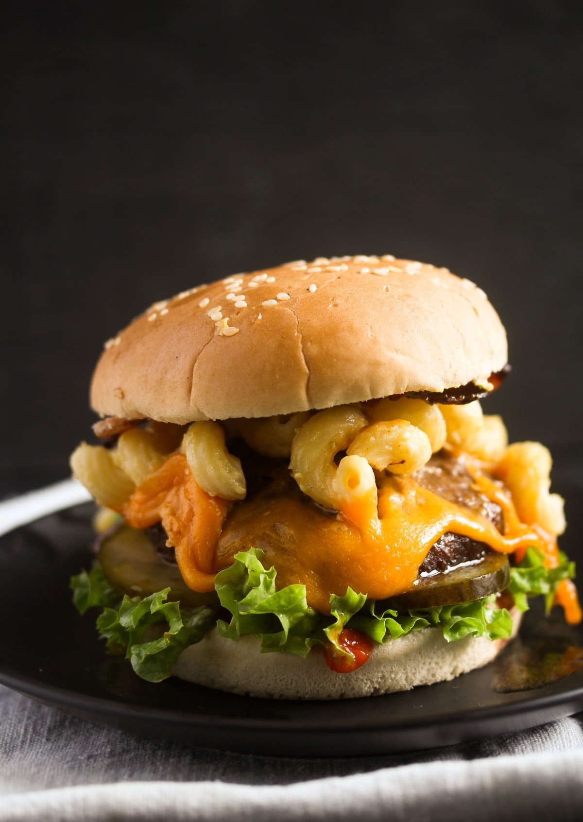 loaded burger with macaroni on a black background.