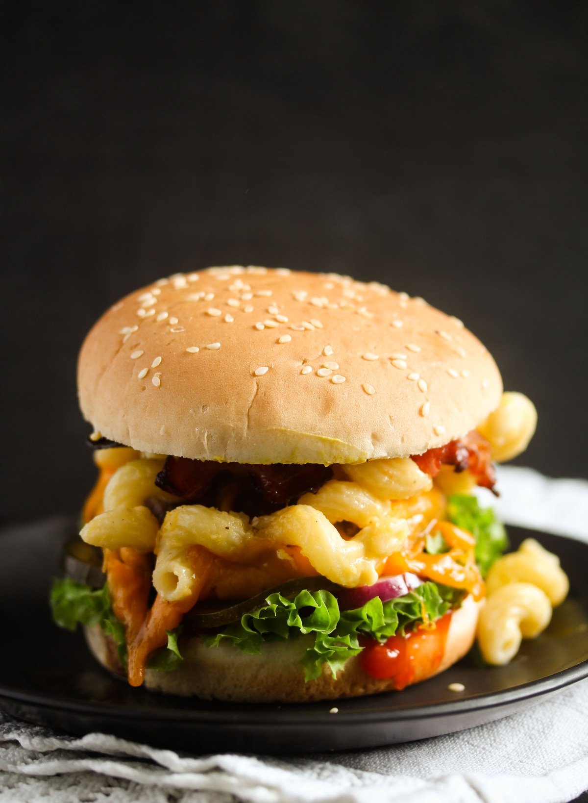 beef burger topped with lettuce, sauce and macaroni and cheese.