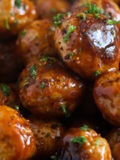 many glossy asian turkey meatballs sprinkled with parsley close up.