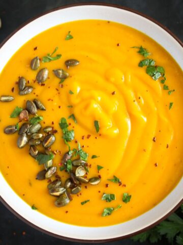 overhead view of a bowl with creamy sweet potato pumpkin soup with pepitas on top.