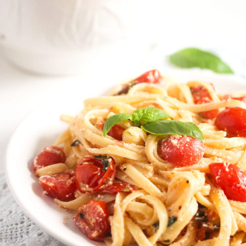 plate full of linguine with cherry tomatoes and basil.