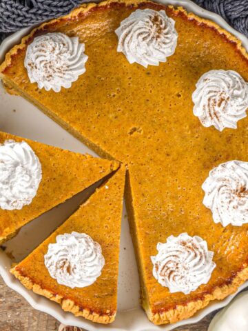 overhead view pumpkin pie with graham cracker crust topped with whipped cream.