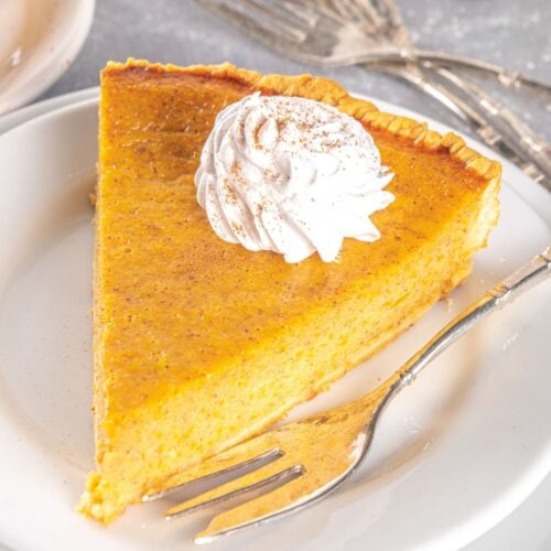 slice of pumpkin pie on a small white plate with a fork.