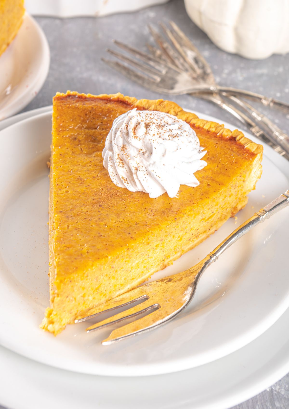 slice of pumpkin pie on a small white plate with a fork.