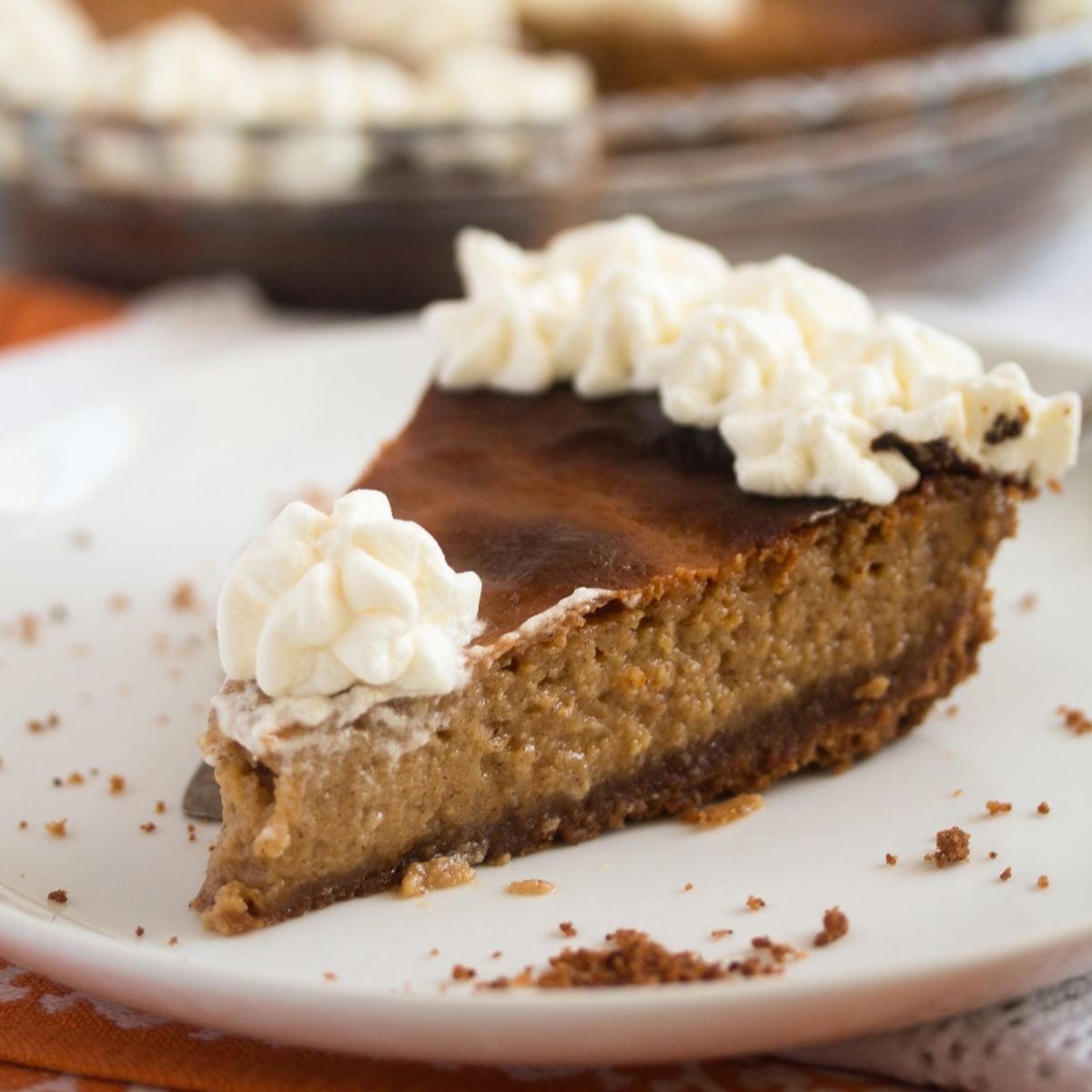 slice of pumpkin pie with pecan crust and topped with whipped cream.