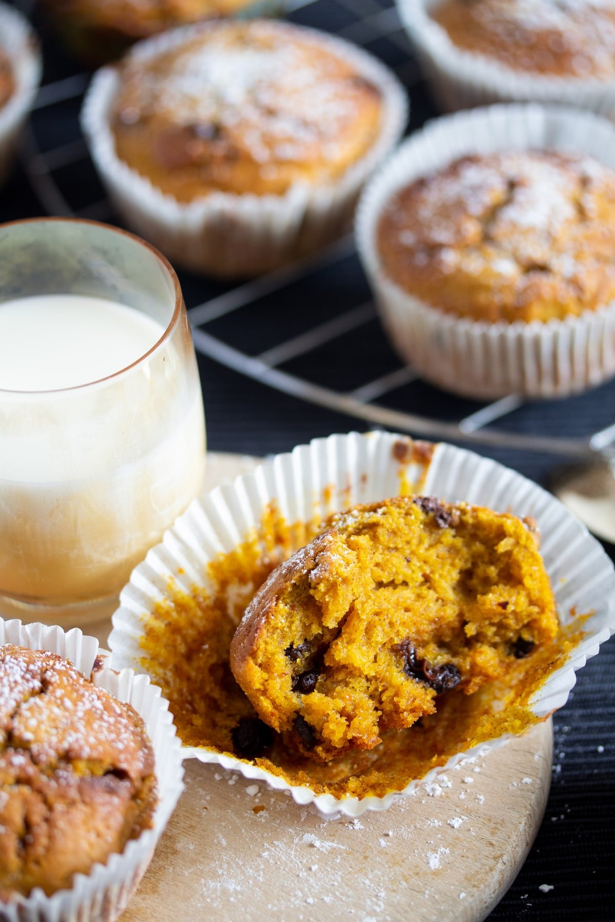 split pumpkin muffin showing the moist crumb and a glass of milk.