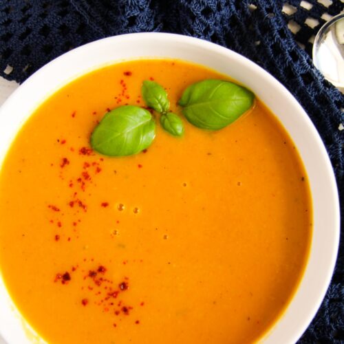 close up sweet potato soup with coconut milk and chili, decorated with basil in a bowl.