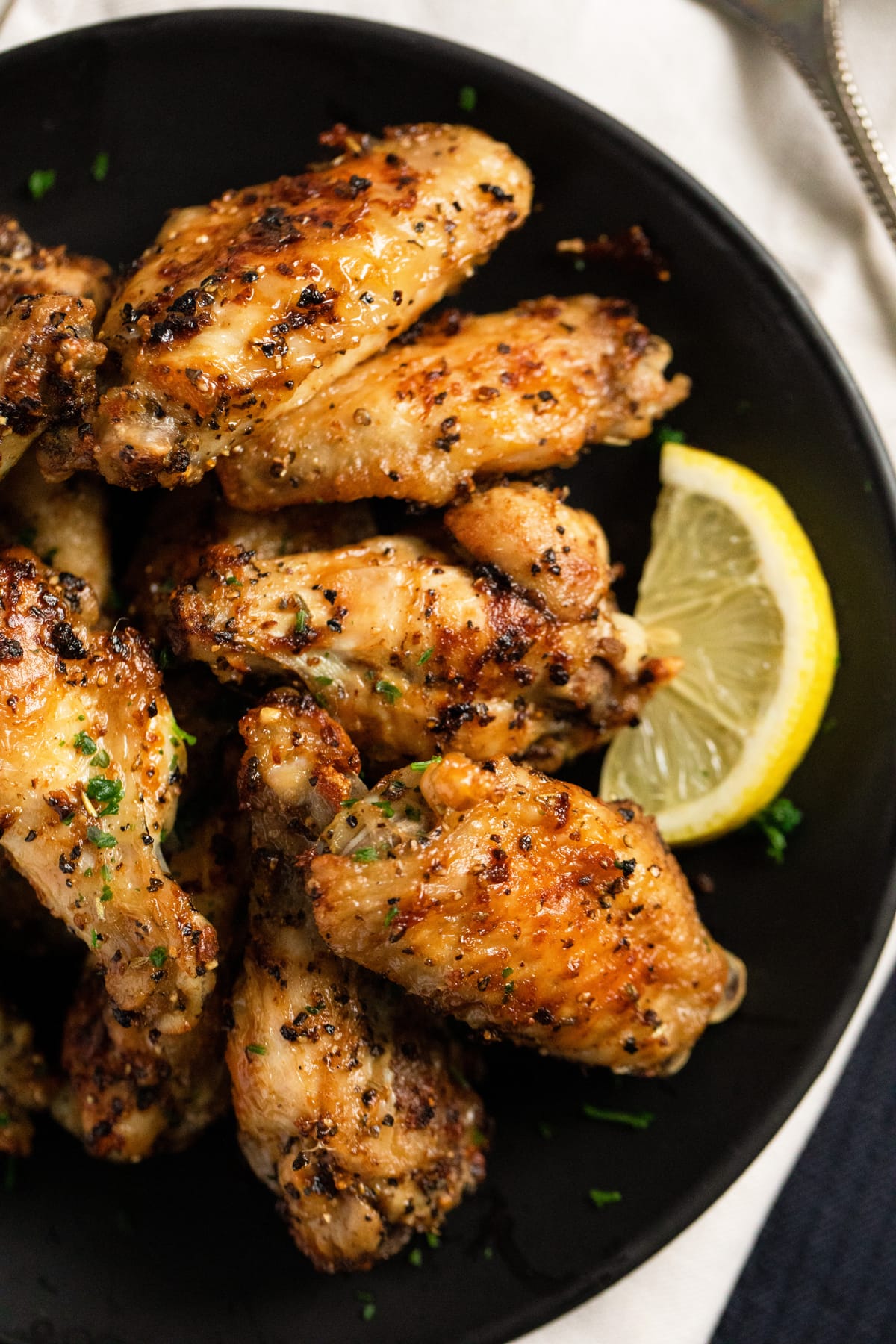 close up of half a plate with crispy wings with lemon pepper seasoning.